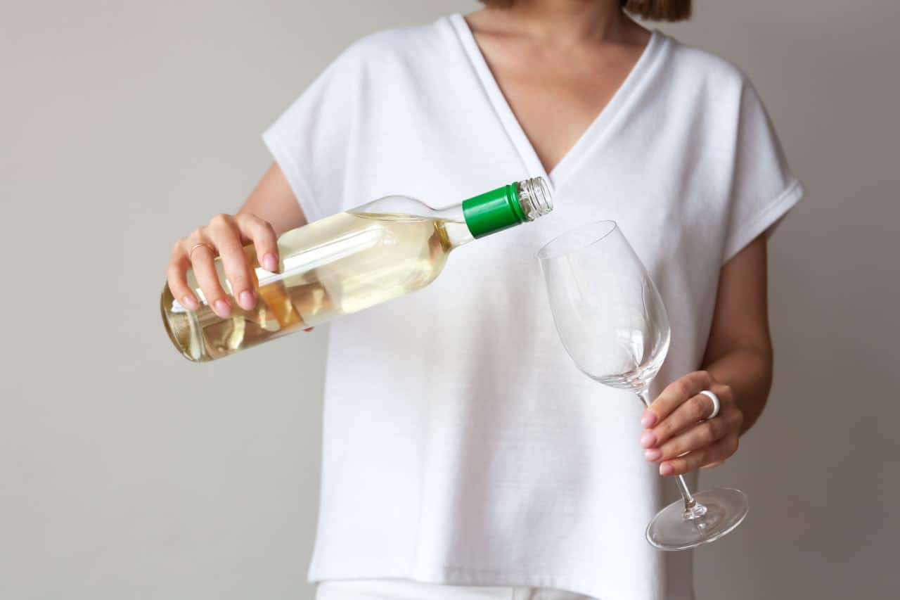 alkohol w kosmetykach - kobieta nalewająca wino do kieliszka